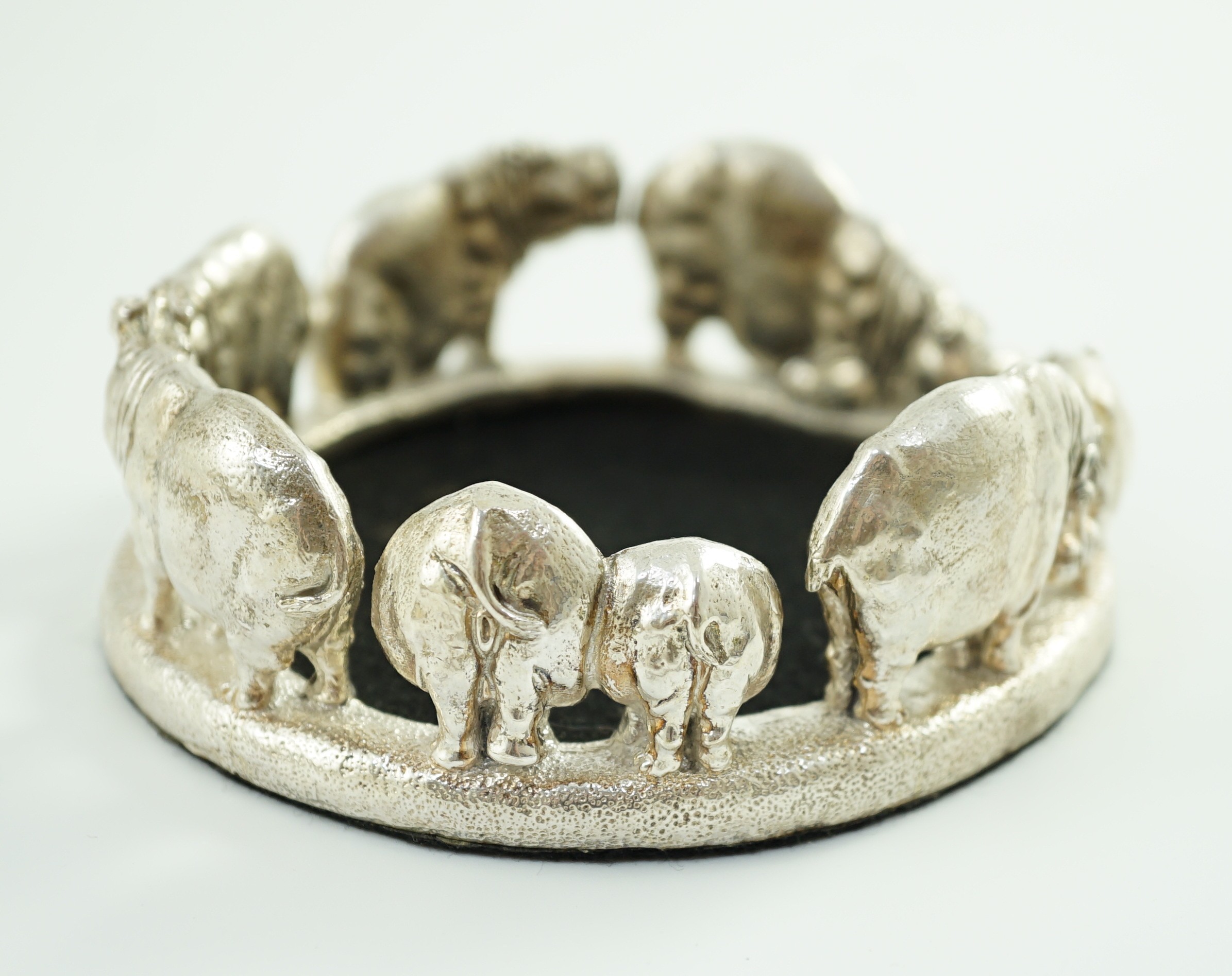 Patrick Mavros - A modern novelty silver bottle coaster, modelled as a continuous bloat of hippopotami, in various positions
